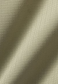 Tejido de un verde claro con textura que presenta un fino patrón de cuadrícula, con una superficie suave y un sutil brillo, cayendo en suaves pliegues.