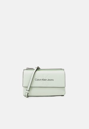 Borsa a mano in pelle verde chiaro con patta pieghevole, tracolla staccabile e logo "Calvin Klein Jeans" impresso sul davanti.