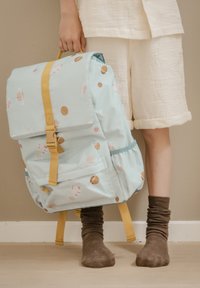 Hellblauer Rucksack mit Klappe, gelben Trägern und einem weltraumthemenbezogenen Muster aus Planeten und Monden. Hergestellt aus glattem, strapazierfähigem Stoff.