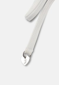 Λευκό υφασμάτινο λουράκι με ραμμένα άκρα και ένα μικρό ασημένιο διακοσμητικό σε σχήμα καρδιάς τοποθετημένο στο τέλος.