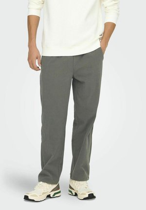 Gray corduroy pants with a straight leg design, featuring textured fabric and side pockets, paired with light-colored athletic shoes.
