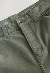 Relaxed fit khaki pants with a button closure, made of soft fabric, featuring visible stitching, and a label indicating size 34R.