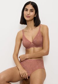 Bra di pizzo color rosa e slip a vita alta coordinati con motivo floreale, dotati di spalline regolabili e dettaglio a svaso al centro.