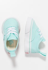 Vaalean teal-väriset kangaskengät, joissa on valkoiset nauhat, kumipohjat ja pieni korko. Takana on vetolenksu ja minimivärityksellä varustettu ompelu.