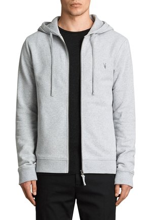 Grå zip-up hoodie gjord av mjukt material, med en framdragbar dragkedja, snörning i huvan och svarta detaljer undertill.