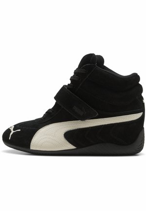 Baskets montantes noires avec bande blanche Puma, fermeture Velcro et lacets, dotées d'un col de cheville rembourré et d'une semelle texturée.