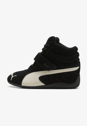 Zapatilla deportiva alta negra con franja blanca Puma, cierre de velcro y cordones, con cuello acolchado suave en el tobillo y suela texturizada.