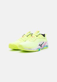 Neon gule sportsko med en tekstureret overdel, sorte accenter og en multicolorer sål med blå og pink detaljer.