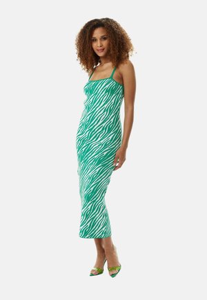 Green zebra-striped midi dress with a fitted design, adjustable straps, and soft, textured fabric. Paired with green open-toe heels.