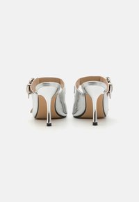 Zilver metallic hoge hakken met een slank ontwerp, voorzien van een puntige neus, slanke stilettohak en een gesp sluiting bij de enkel.