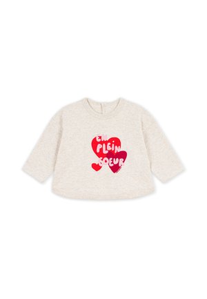 Cremefarbenes Baby-Langarmshirt mit drei roten Herzen und französischem Text "EN PLEIN COEUR" auf der Vorderseite.