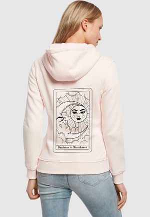 Felpa rosa chiaro realizzata in materiale morbido, con una grafica di un volto con cuori ed elementi celestiali sul retro.