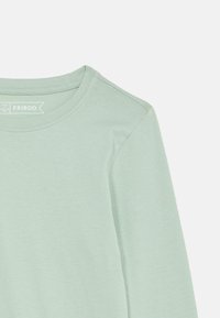 Šviesiai žalia ilgomis rankovėmis medvilninė marškinėliai su apvaliu iškirpimu, dydis 9/10 metų, prekės ženklas Friboo, padėti ant baltos fono.