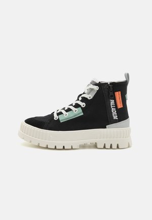 Zapatillas altas de lona negra con cordones blancos, que cuentan con un acento en verde menta, cierre con cremallera y una gruesa suela de goma blanca.