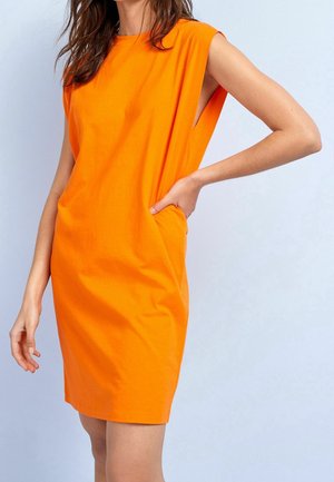 Pomarańczowa bawełniana sukienka o bezrękawowym fasonie, z boczną kieszenią, luźnym kroju i gładką teksturą. Minimalistyczny styl bez dodatkowych wzorów czy akcentów.