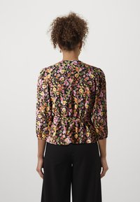 Blusa floreale con maniche a trequarti, sfondo nero, stampa floreale colorata in rosa, arancione e giallo, dettaglio in vita a peplo, legata sul retro.