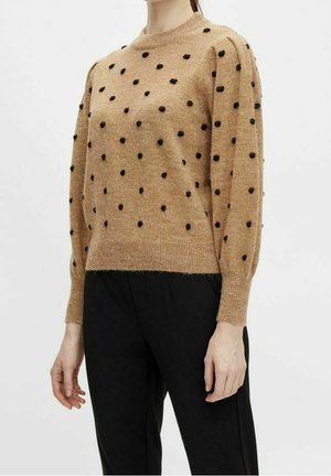 Brauner Strickpullover mit schwarzen Punkten, Rundhalsausschnitt und leicht puffierten Ärmeln. Kombiniert mit schwarzen Hosen, zeichnet sich durch eine weiche Textur aus.