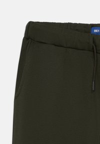 Olivgrüne Jogginghosen aus einem weichen, strukturierten Stoff. Mit einem elastischen Bund, Kordelzug und Seitentaschen für Stauraum.