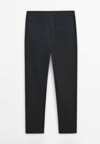 Zwarte, aansluitende broek van polyester. Heeft een elastische tailleband en twee achterzakken. Gladde textuur, geen zichtbare patronen of hardware.