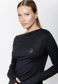 Czarny longsleeve wykonany z gładkiego materiału, z okrągłym skórzanym logo na piersi oraz dekoltem typu off-shoulder.