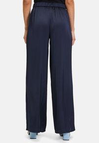 Granatowe spodnie o szerokich nogawkach z elastycznym pasem, wykonane z gładkiego materiału; długość do kostek z luźnym krojem i minimalistycznym stylem.