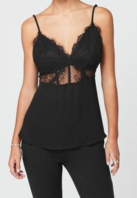 Camiseta negra sin mangas con detalles de encaje, con escote en V, tirantes ajustables y un panel central semitranslúcido. Tejido suave con un ajuste fluido.