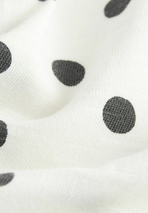 Valkoinen kangas mustilla pilkuilla, jolla on pehmeä rakenne ja kevyt laskeutuminen. Pilkut vaihtelevat kooltaan ja ovat tasaisesti jakautuneet kankaan pinnalle.