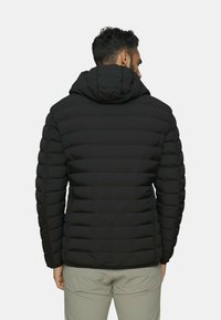 Giacca imbottita nera con cappuccio, caratterizzata da sezioni trapuntate e un design elegante. Il materiale appare lucido e leggero.