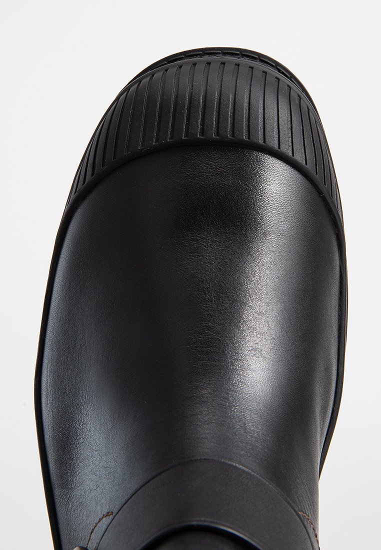 Schwarzer Lederstiefel mit glatter Oberfläche, ausgestattet mit einer gerippten Gummikappe und abgerundeter Form, die Haltbarkeit und Schutz hervorhebt.