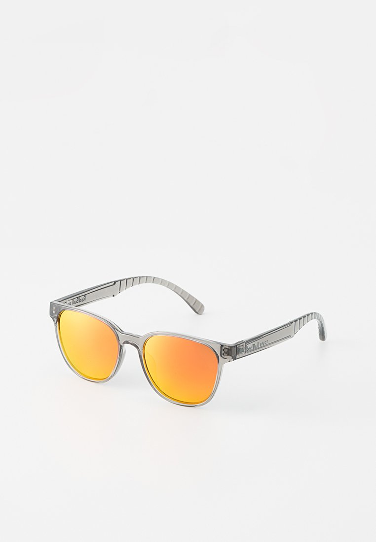 Okulary przeciwsłoneczne z przezroczystą szaro-skalną ramką, pomarańczowymi lustrzanymi soczewkami, kanciastym kształtem, teksturowanymi zausznikami oraz detalami marki po boku.