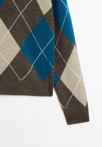 Section de manche de pull avec un motif losange argyle marron, beige et bleu, souligné par des lignes blanches en pointillés.