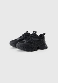 Black athletic shoes featuring mesh panels, textured rubber soles, and a chunky design with curved accents and reinforced toe caps.