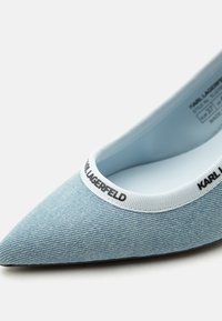 Μπαλαρίνα με μυτερή μύτη από ανοιχτό μπλε τζιν ύφασμα με λευκή ελαστική επένδυση και μαύρο κείμενο "KARL LAGERFELD".