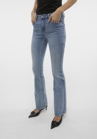 Lyseblå bootcut jeans laget av denim, med et klassisk fem-lomme design og midjehøyde. Kombinert med svarte spisse sko.