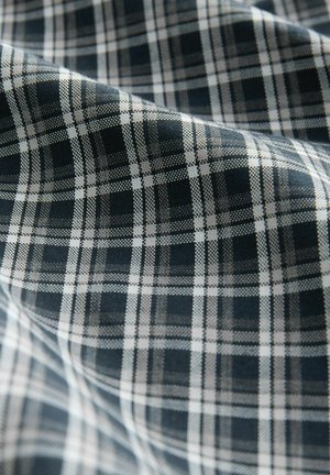 Marinblå och vit rutig tyg med en strukturerad, vävd textur, som har konsekventa horisontella och vertikala linjer som bildar ett rutig mönster.