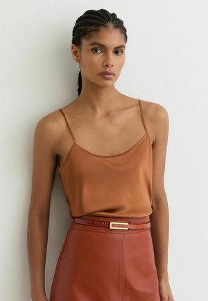 Bruine satijnen cami-top met smalle bandjes gecombineerd met een hoog getailleerde leren rok met een gestructureerde riem en gouden hardware-accent.