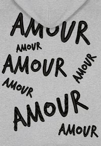 Felpa grigia con testo ricamato in nero "AMOUR" in diverse dimensioni e stili, creando un motivo sparso sul tessuto.