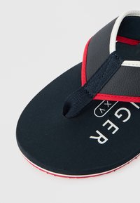 Must Musted muste, misrih muste, valge logo. Thong rihm on valmistatud vastupidavast materjalist punaste aktsentidega.