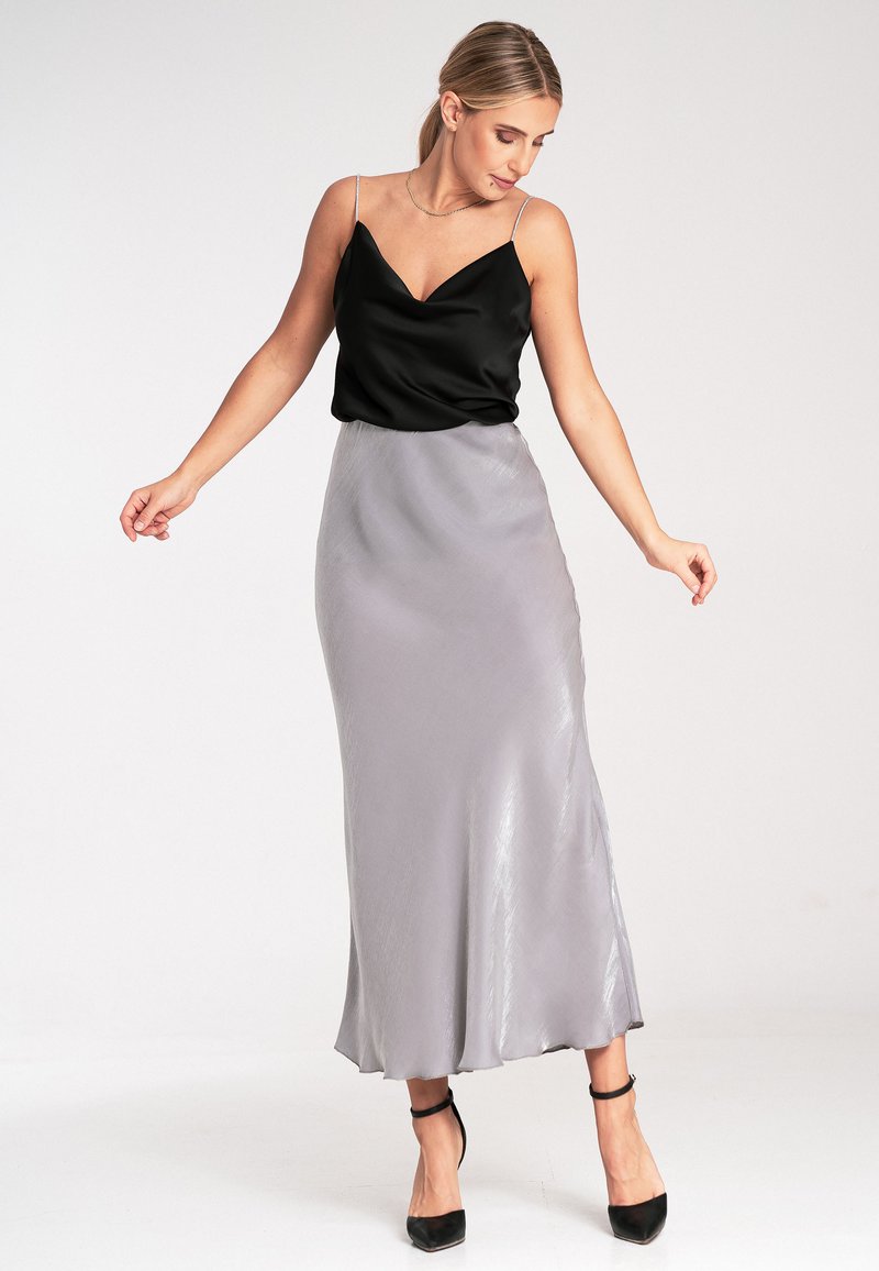 Schwarzes Satin-Camisole-Top mit dünnen Trägern, kombiniert mit einem hellgrauen Seiden-Maxikleid mit einer glatten, fließenden Textur. Schwarze Absätze.