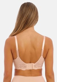 Vaaleanpunainen pitsirintaliivi, jossa on teksturoitu selkä, säädettävät olkaimet ja monihakasuljin. Materiaali sisältää kukkakuvioita ja kuusikulmioita.