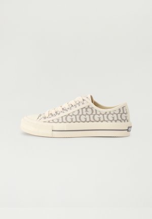 Sneaker in tela beige con un motivo a logo ripetuto, suola in gomma piatta e lacci a contrasto. Punta arrotondata e finitura testurizzata sui lati.