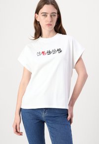 Balta medvilninė marškinėliai su trumpomis rankovėmis, puošti spalvingu grafiniu dizainu, kuriame pavaizduoti keturi stilizuoti katinai per krūtinę. Standartinis dydis.