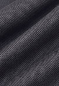 Teksturowana czarna tkanina o plecionym wzorze, charakteryzująca się miękkim matowym wykończeniem i widocznymi fałdami, które podkreślają jej elastyczność i strukturę.