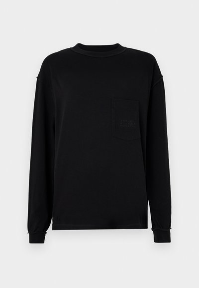 Črna dolgobojna majica iz bombaža z okroglim izrezom, žepom na levem prsnem delu in rebrastimi manšetami z blagim nabiranjem.