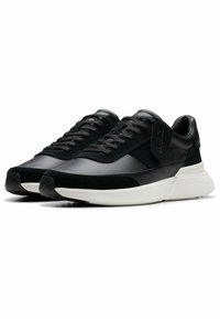 Zapatillas negras con una combinación de materiales de piel y ante, que cuentan con una suela texturizada, puntera redondeada y cordones negros.