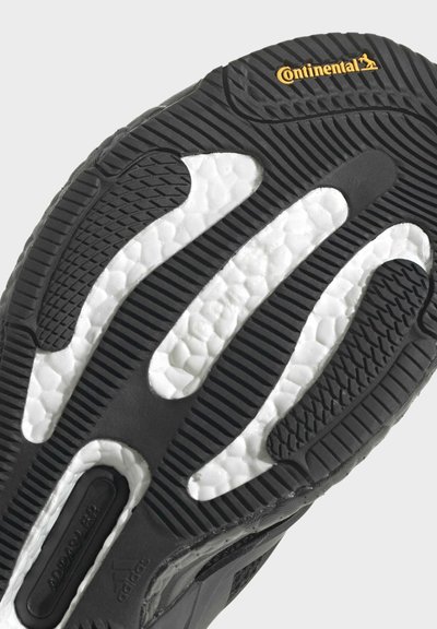Semelle en caoutchouc noir avec des accents texturés blancs. Présente un design à motifs pour l'adhérence et inclut un logo Continental.