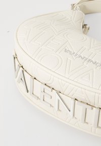 White leather handbag featuring embossed branding, a curved shape, and a silver hardware accent with the name "VALENTINO."