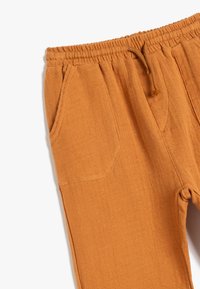 Orange linned bukser med en struktureret overflade, elastisk talje og snor, med to forlommer og en afslappet pasform.