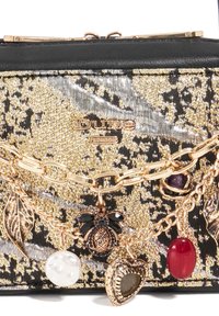 Black and gold handbag with metallic sheen, featuring a chain with decorative charms, including a leaf, a pearl, and a heart-shaped pendant.