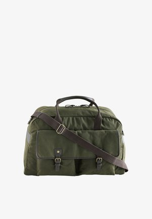 Sac de voyage en toile verte avec bandoulière réglable marron foncé, deux poches avant à boucle et deux poignées supérieures.